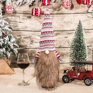 Close-up of knit Christmas gnome wine bottle cover with long beard on festive wood background