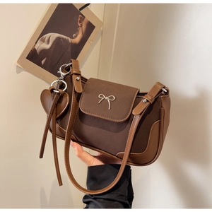 Dettaglio della borsa vintage marrone con fiocco argentato e ciondolo a forma di cuore