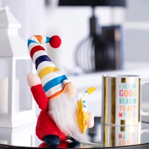 Rainbow striped gnome plush doll with long white beard on a reflective surface