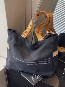 Minimalist black canvas tote bag with large capacity and stylish yellow lettered straps