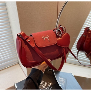 Dettaglio borsa in pelle rossa con fibbia a fiocco d'argento e ciondolo a cuore