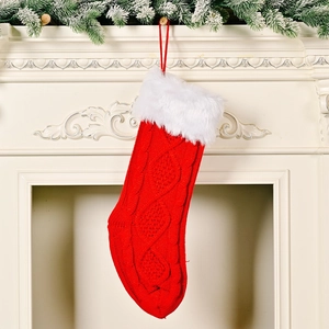 Klassischer roter Strick-Weihnachtsstrumpf mit weißem Kunstpelzbesatz am Kamin