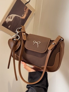 Borsa a spalla marrone vintage con fibbia a fiocco argento e ciondolo a cuore su bianco