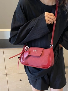 Piccola borsa vintage bordeaux con fiocco in metallo e ciondolo a cuore su una modella