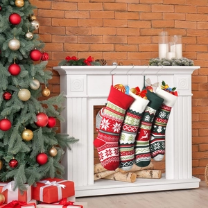 Set of four knitted Christmas stockings with elk and snowflake patterns on white mantel