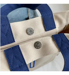 Detailed close-up of textured metal magnetic clasp on a heavy canvas tote bag