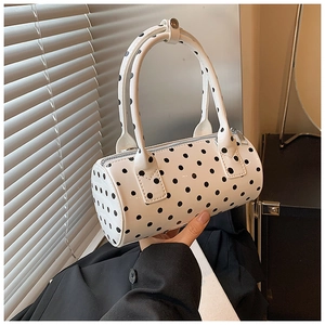 Detailed view of a white Boston handbag with black polka dots and dual top handles
