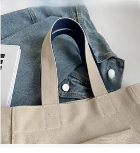 Detail of beige canvas tote bag with dual-tone straps and reinforced stitching