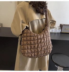Detail of coffee quilted bubble tote bag with pleated strap worn by a model