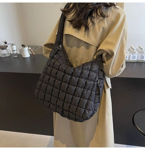 Detail of black quilted puffer tote bag shown in a minimalist lifestyle setting