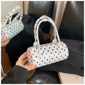 Detailed mirror reflection of a chic polka dot patent leather cylinder handbag with silver zipper