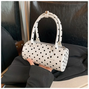 Close-up of a white polka dot Boston handbag with sleek patent leather finish and top handles