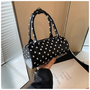 Detailed shot of a black glossy patent leather Boston bag with white polka dots