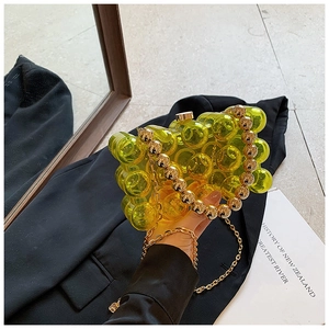Dettaglio borsa a mano in acrilico giallo perlato con manico a sfere dorate