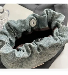 Detail of blue denim bucket bag featuring quilted texture and silver magnetic snap closure