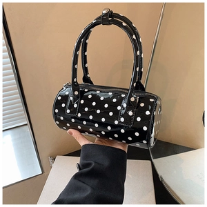 Close-up of black patent leather Boston bag with white polka dots and silver metal hardware