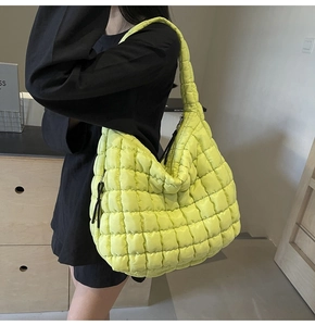 Detail view of large quilted puffer tote bag in neon yellow green with adjustable shoulder strap