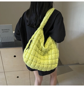 Detail of a bright green quilted bubble tote bag featuring large diamond stitching and a zipper