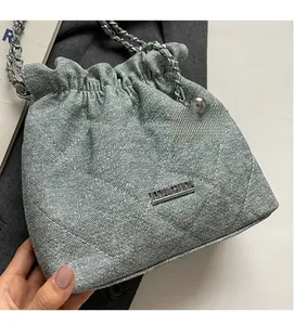 Detailed macro view of quilted blue denim bucket bag with silver metal chain strap