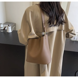 Detailansicht der braunen Leder-Beuteltasche mit Lychee-Muster getragen von einem Model