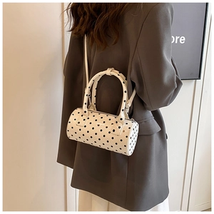 Rear view of a model carrying a white polka dot Boston bag with black handles