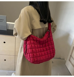 Detailed back view of a large rose red quilted puffer tote bag on a person's shoulder