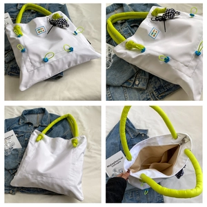 Detail view of white nylon tote bag with neon green padded handle and interior pocket