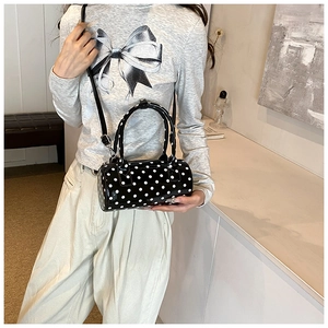 Close-up of black polka dot cylinder bag shown with a stylish casual outfit