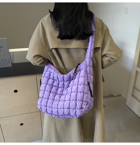 Rear view of purple quilted puffer tote bag worn on shoulder with a beige trench coat