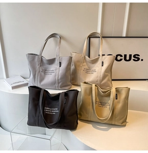 Detail showing four canvas tote bags in grey, beige, black, and khaki on a white podium