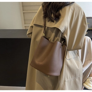 Detail der dunkelbraunen Eimer-Tasche aus Leder mit goldener Hardware und Prägung