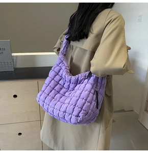 Detailed side view of the purple quilted cloud bag with padded texture and sleek black zipper