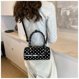 French style polka dot Boston handbag with shiny finish shown on shoulder in soft light