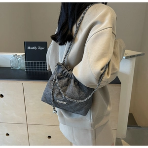Detail of dark grey tweed bucket bag with silver chain strap and drawstring closure