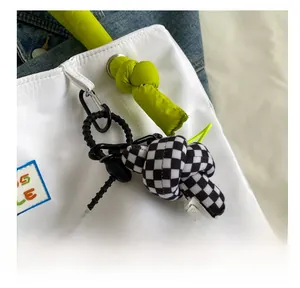 Detail of neon green and checkerboard knotted bag charms with black carabiner clip