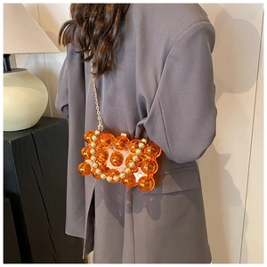 Dettaglio borsa da sera in perle acriliche ambra con elegante catena in metallo