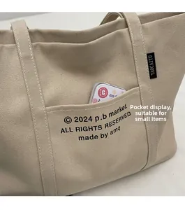 Close-up of beige canvas tote bag front pocket showing texture and brand label