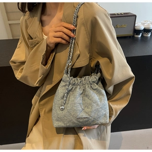 Detail of silver bucket bag with quilted rhombic pattern and metal chain strap