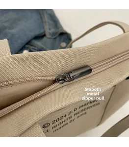 Close-up of smooth metal zipper puller and canvas texture on a large tote bag