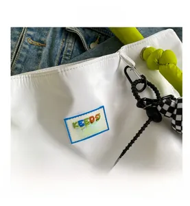 Detail of white tote bag with colorful Keep Smile patch and green knot handles