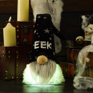 Close-up of glowing Halloween gnome with black EEK hat among spooky rustic decorations