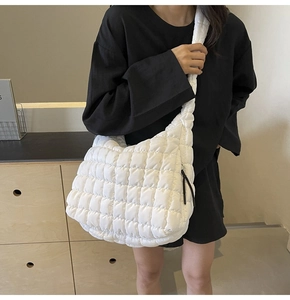 Detail of white quilted puffy tote bag featuring textured grid pattern and wide shoulder strap