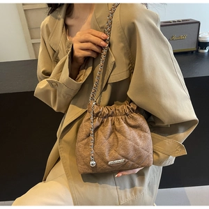 Detail of brown quilted tweed bucket bag with silver metal plate and chain strap