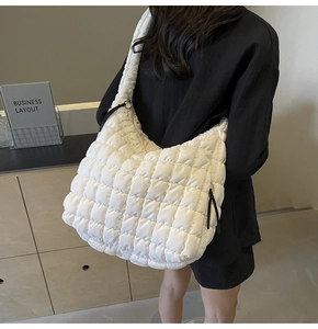 Detailed view of the white quilted puffer tote bag worn by a model in a fashion setting