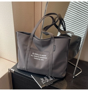 Close-up of deep grey canvas tote bag with white minimalist typography and textile label