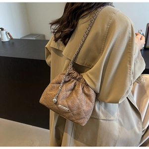 Brown quilted bucket bag detail with metal logo and silver chain strap on khaki coat
