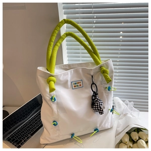 Detailed close-up of a white nylon tote bag featuring green padded handles and Keedo logo