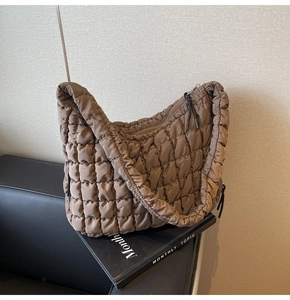 Detail of quilted puffy tote bag in brown with sleek nylon texture and zipper