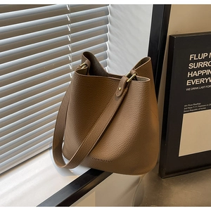 Detail der braunen Eimer-Tasche mit Leder-Narbenstruktur und Metallschnallen