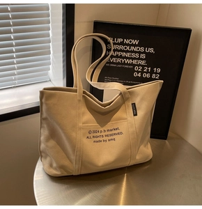 Detail of canvas tote bag showing side seam label and the front printed copyright logo
